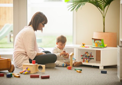 Teacher and child playing with toys on floor